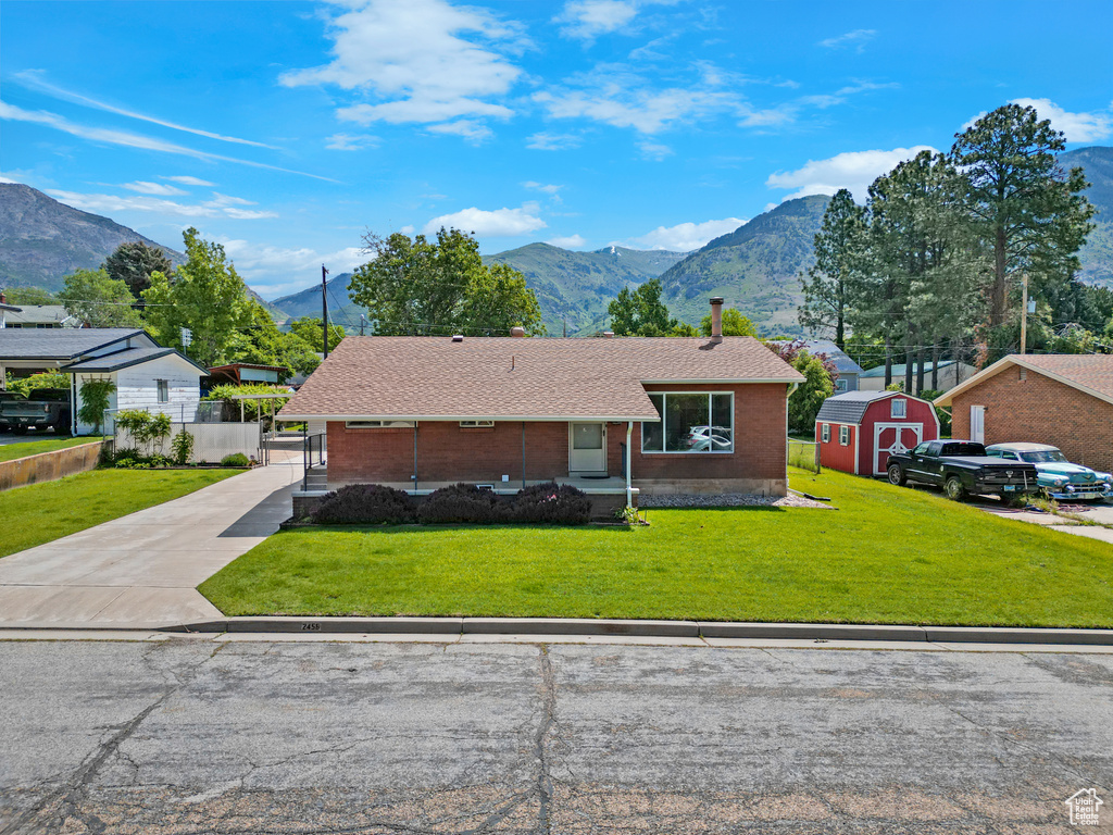 View of front of house with a mountain view, a front lawn, brick siding, driveway, and a shingled roof