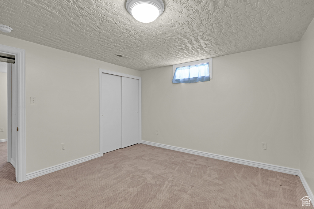 Basement featuring carpet floors, a textured ceiling, and baseboards