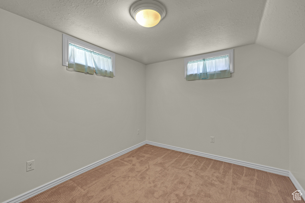 Basement with a textured ceiling, light colored carpet, and baseboards