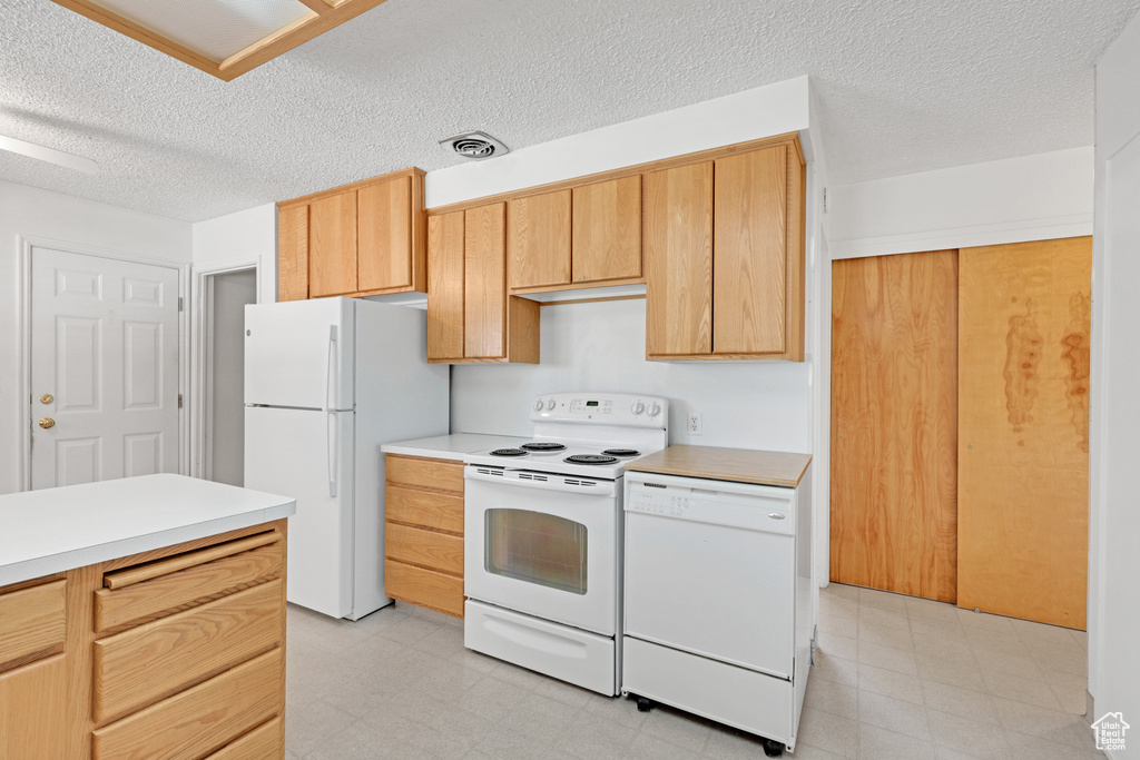 Kitchen with white appliances, light floors, light countertops, and a textured ceiling