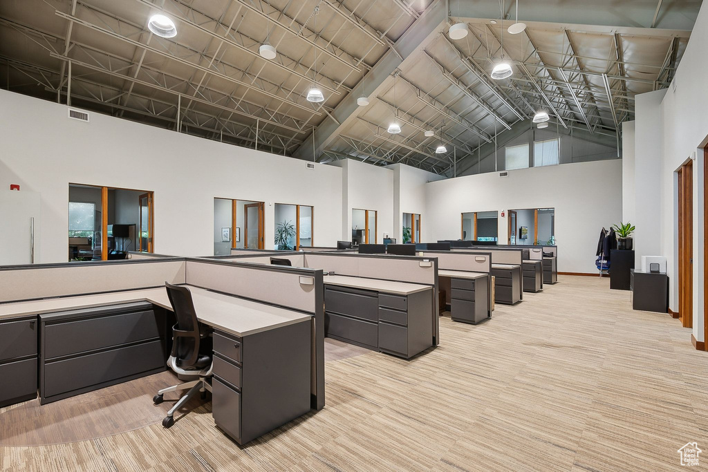 Office space featuring high vaulted ceiling and light colored carpet