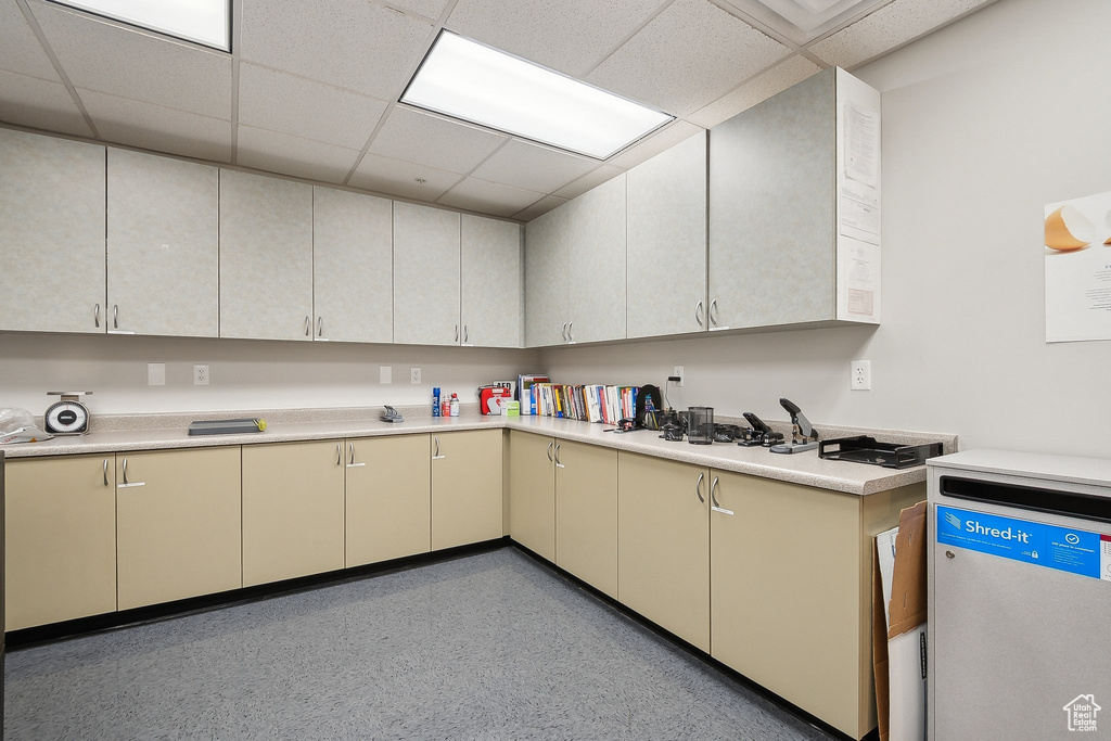 Kitchen featuring light countertops, cream cabinets, a paneled ceiling, and dark speckled floor