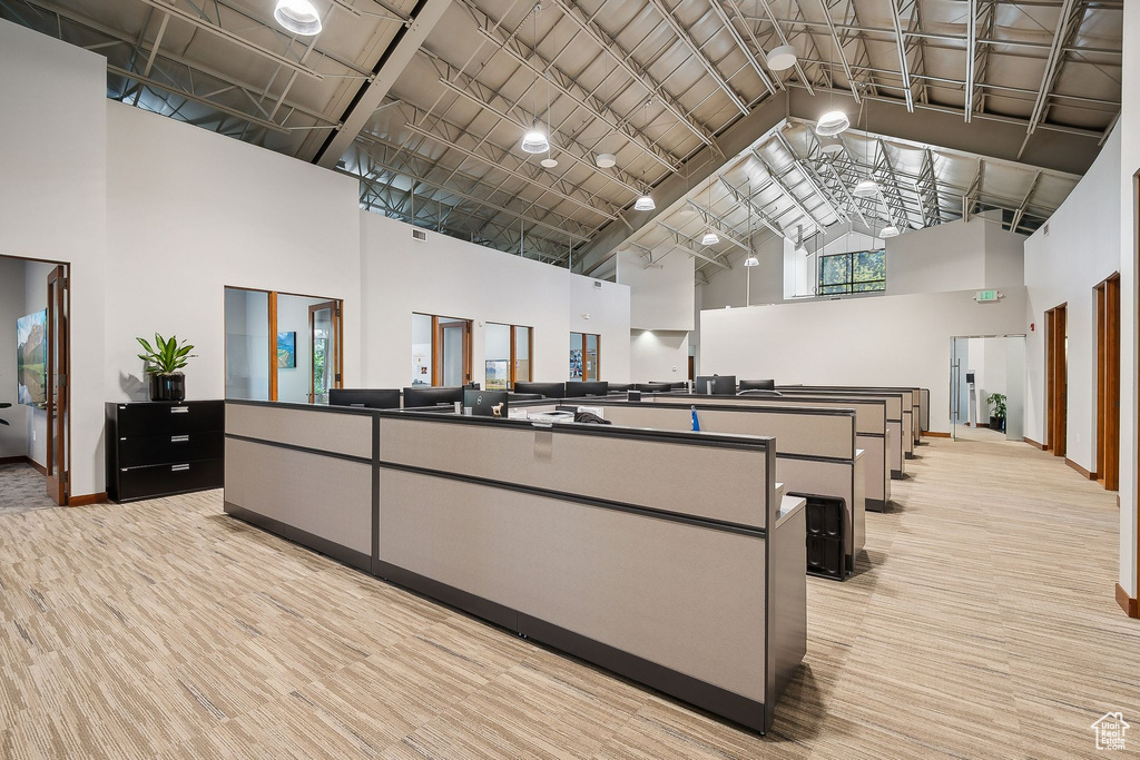 Misc room featuring high vaulted ceiling, baseboards, and light carpet