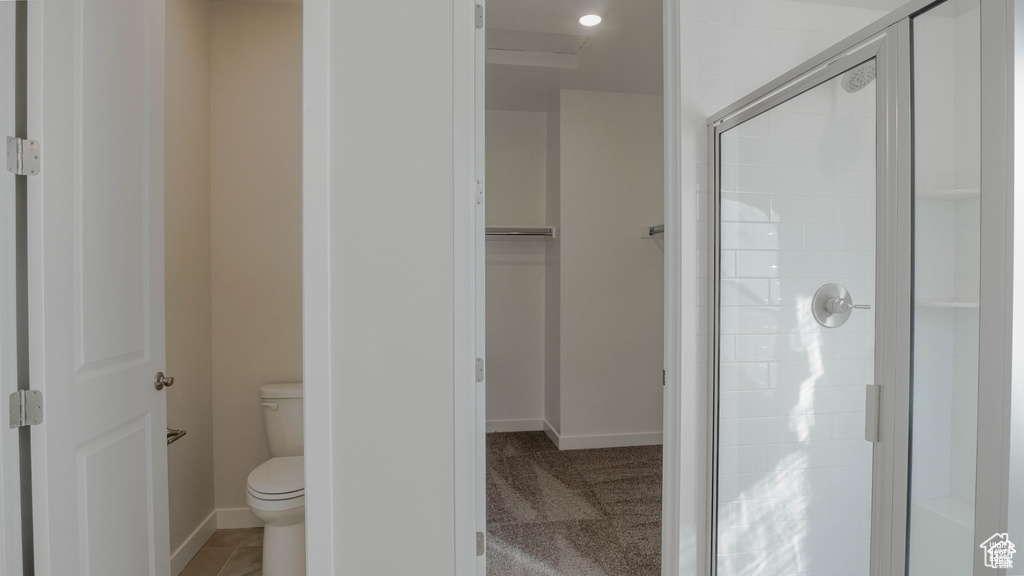 Full bath featuring toilet, a shower stall, and baseboards