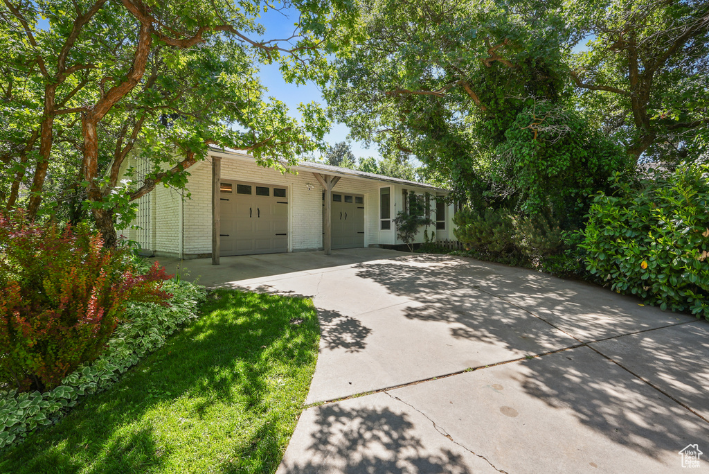 View of front of property with brick siding, concrete driveway, and an attached garage