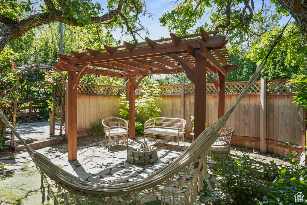 Fenced backyard featuring a patio, a pergola, and a fire pit
