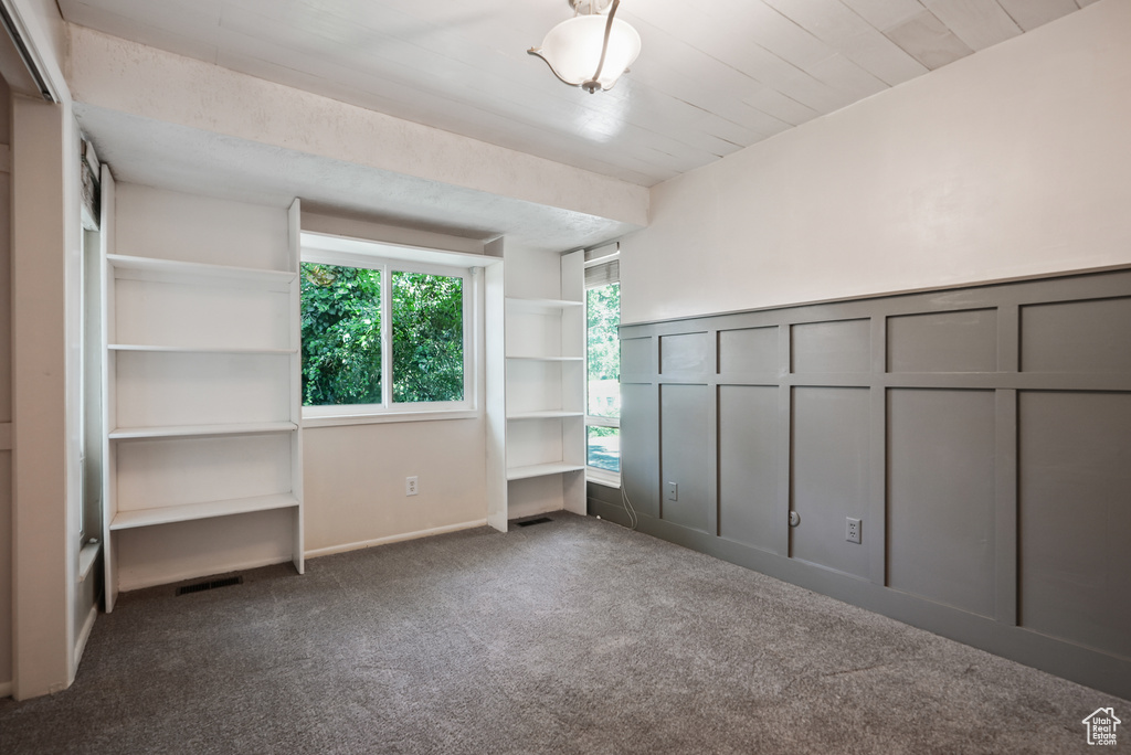 Unfurnished bedroom featuring carpet flooring, a decorative wall, and a wainscoted wall