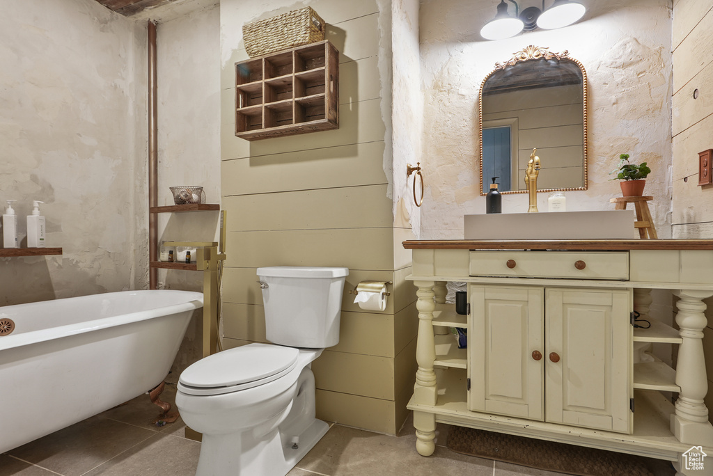 Bathroom with a soaking tub, vanity, toilet, and tile patterned floors