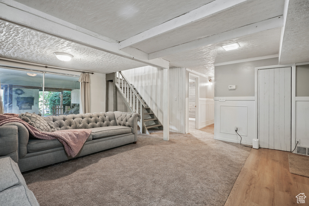 Living area featuring stairs, wainscoting, wood finished floors, a textured ceiling, and a decorative wall