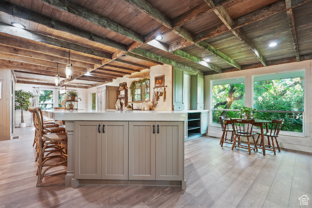 Kitchen with gray cabinets, light countertops, light wood-type flooring, plenty of natural light, and wooden ceiling with exposed beams