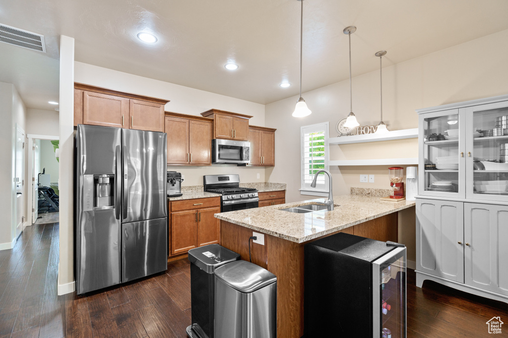 Kitchen with appliances with stainless steel finishes, a sink, a peninsula, brown cabinets, and recessed lighting