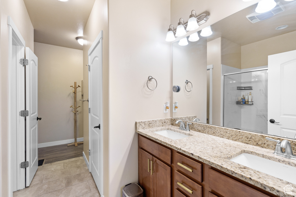 Full bath featuring double vanity, a shower stall, and tile patterned floors