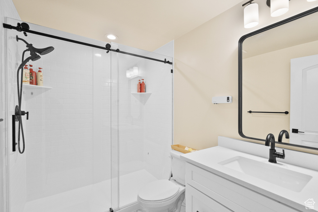 Bathroom with toilet, vanity, a stall shower, and recessed lighting