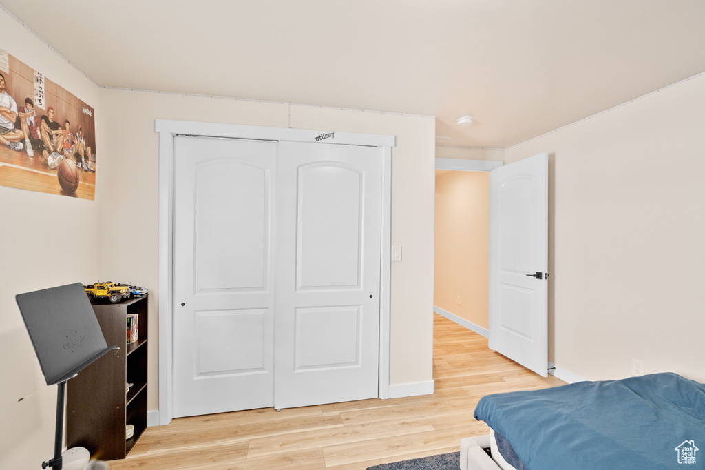 Bedroom featuring light wood-style floors, a closet, and baseboards