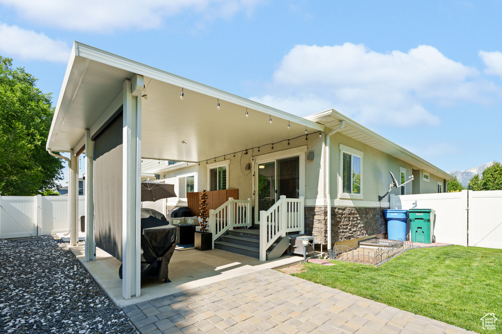 Back of house with a gate, a patio, and stone siding