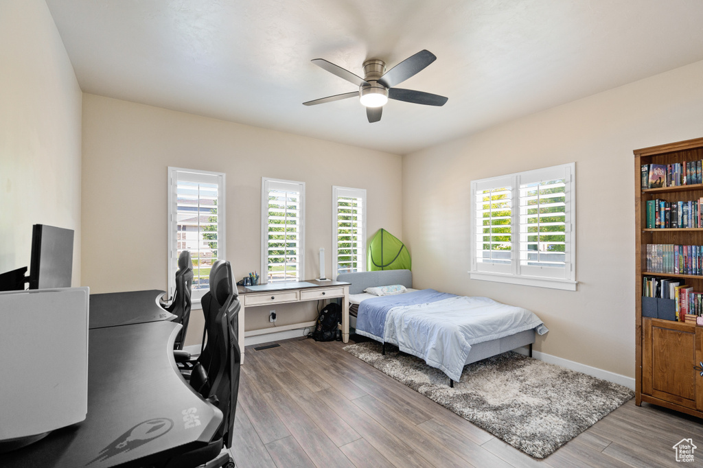 Bedroom with wood finished floors, a desk, baseboards, and ceiling fan