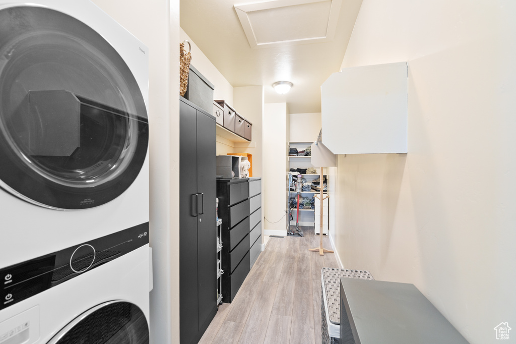 Washroom featuring estacked washer and dryer, light wood-type flooring, and attic access
