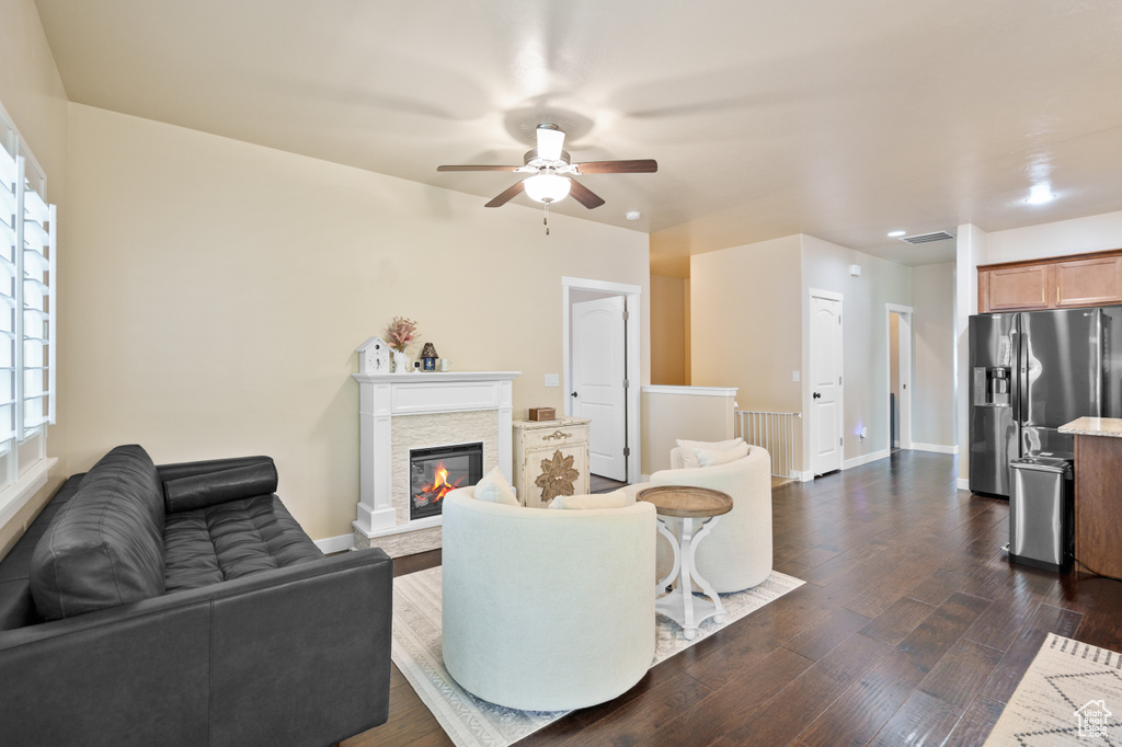 Living area with a ceiling fan, dark wood-type flooring, a fireplace, baseboards, and recessed lighting