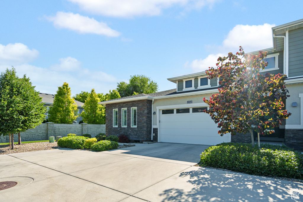 View of front of property with concrete driveway, stone siding, and stucco siding