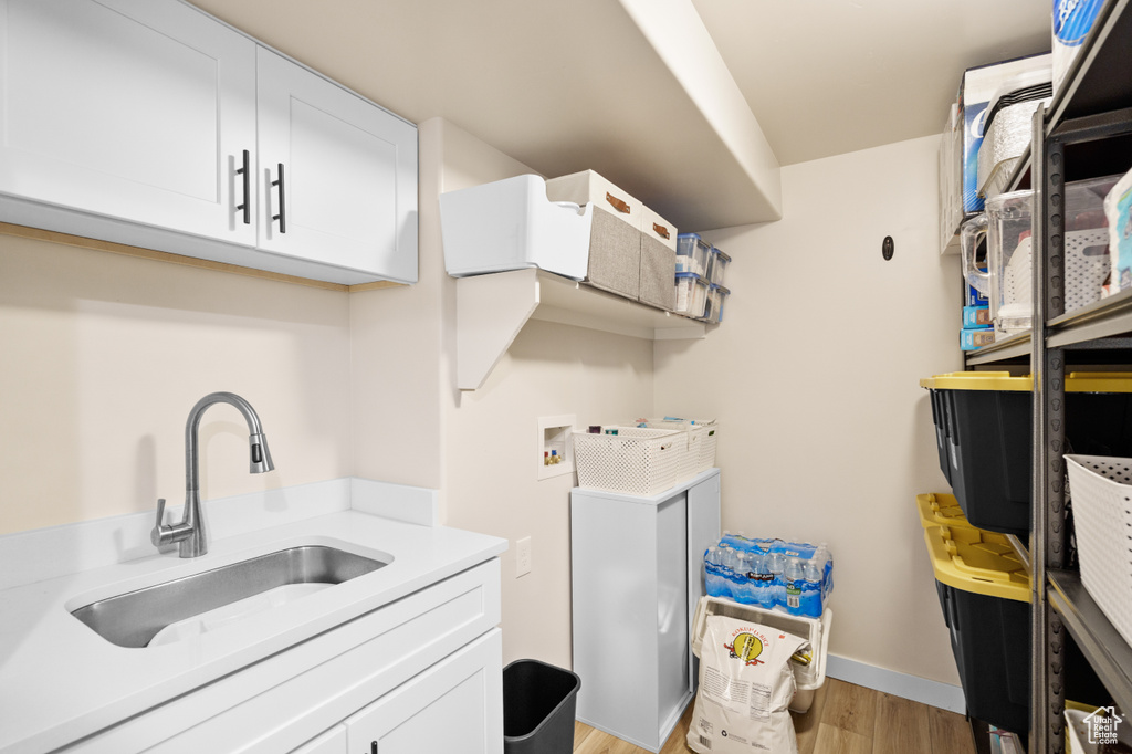 Laundry room with washer hookup, cabinet space, light wood finished floors, and baseboards