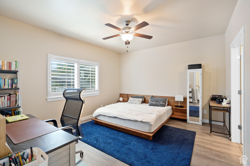 Bedroom with light wood finished floors, a ceiling fan, and baseboards