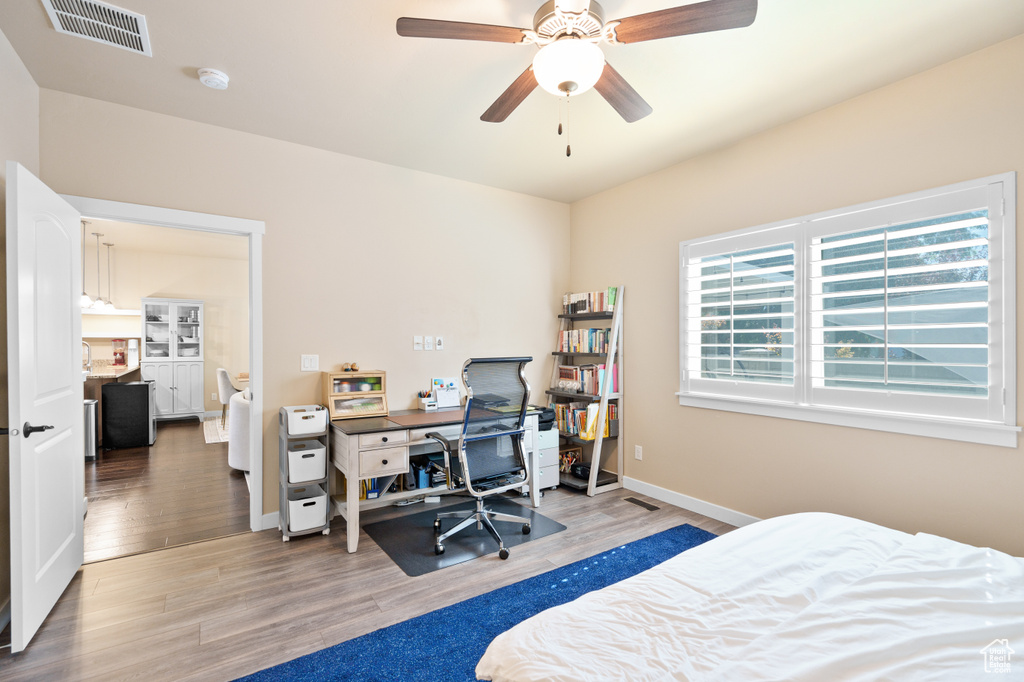 Bedroom featuring light wood-style flooring, baseboards, a desk, and a ceiling fan