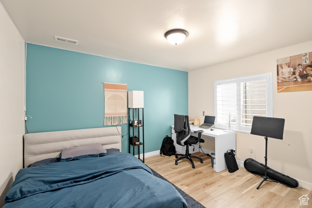 Bedroom with wood finished floors, a desk, and baseboards