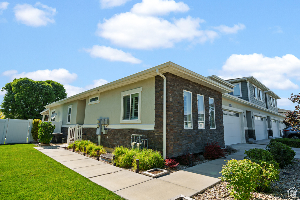 View of front of house with stone siding, stucco siding, and concrete driveway