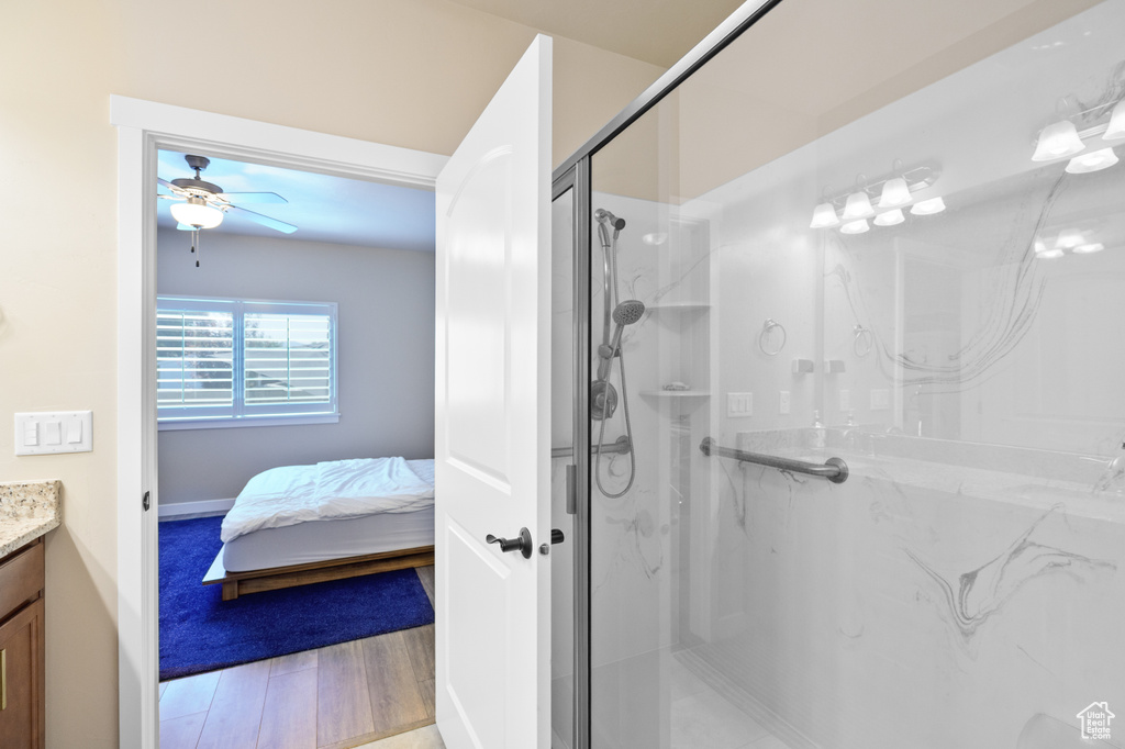 Bathroom with vanity, a ceiling fan, a marble finish shower, and wood finished floors