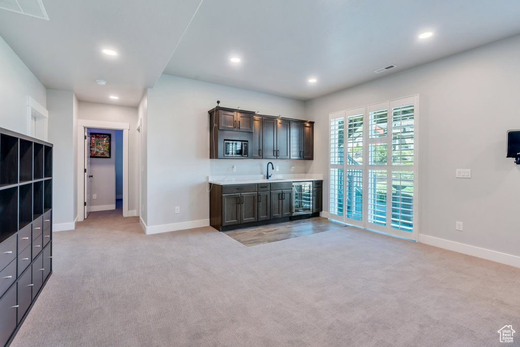 Indoor wet bar with stainless steel microwave, baseboards, recessed lighting, light colored carpet, and wine cooler