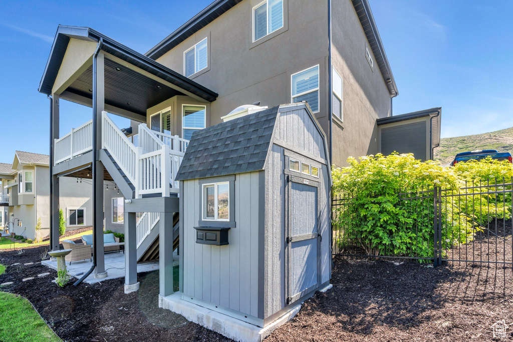 View of property exterior with stairs, a patio area, and roof with shingles