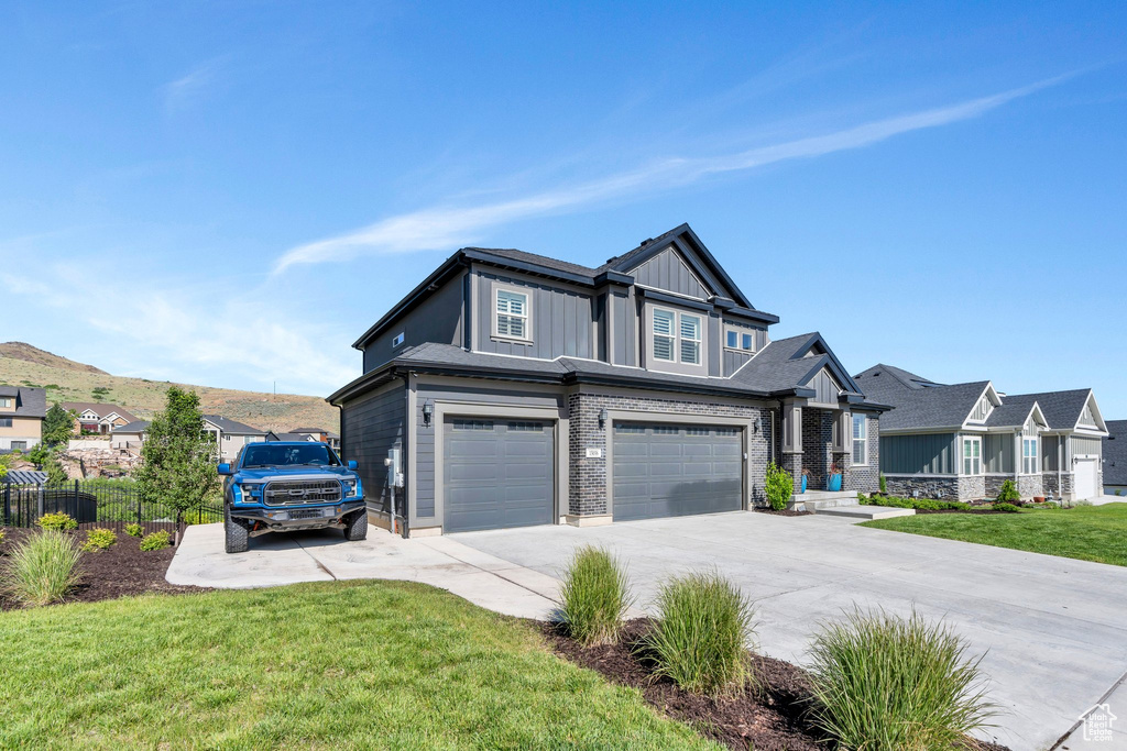 View of front of house with a garage, board and batten siding, driveway, and a residential view