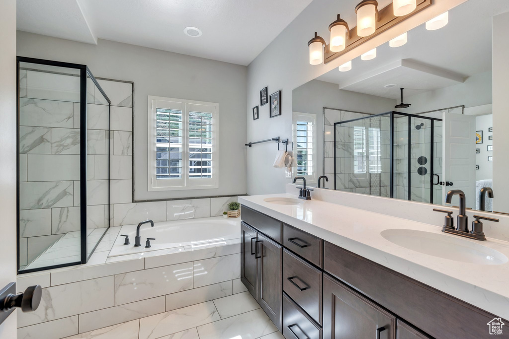 Full bathroom featuring a stall shower, marble finish flooring, a bath, and double vanity