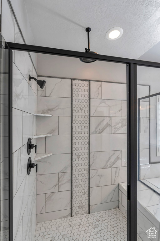 Bathroom with a shower stall and a textured ceiling