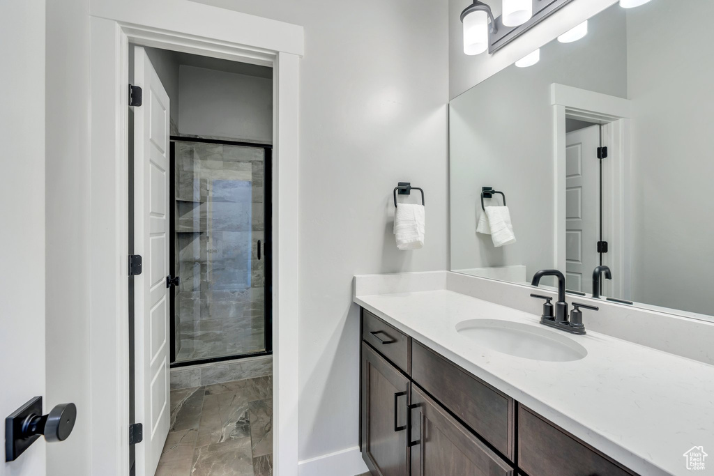 Full bath with vanity, a stall shower, baseboards, and marble look tiles