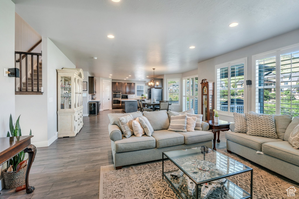 Living room featuring recessed lighting, dark wood-style flooring, baseboards, stairs, and a chandelier