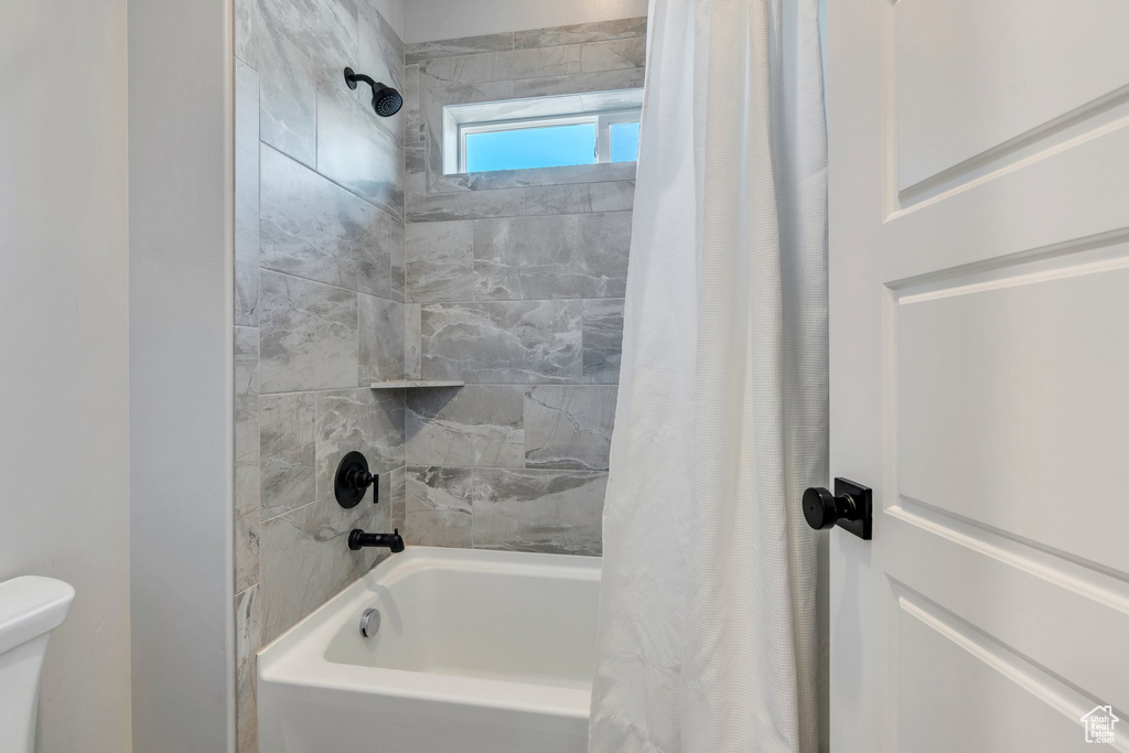 Bathroom featuring shower / tub combo with curtain and toilet