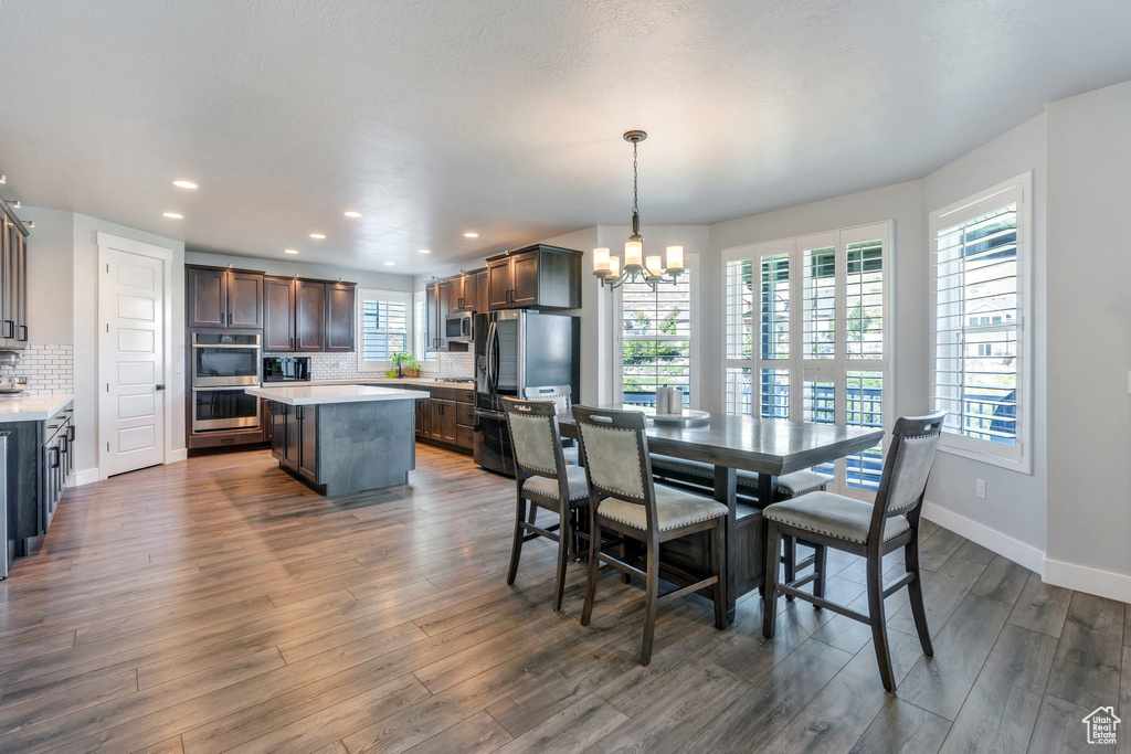 Dining space with a chandelier, dark wood-type flooring, baseboards, and recessed lighting