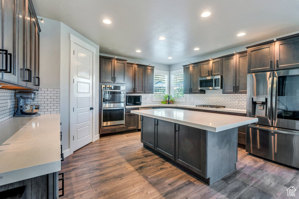 Kitchen with stainless steel appliances, tasteful backsplash, light countertops, recessed lighting, and dark wood finished floors