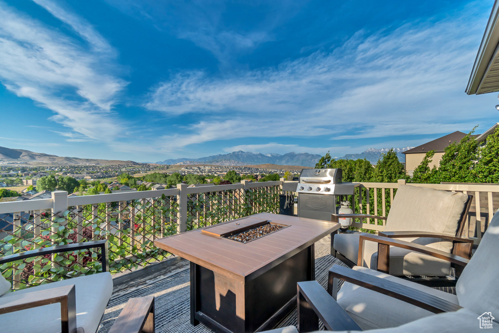 Wooden terrace with a mountain view, a fire pit, and grilling area