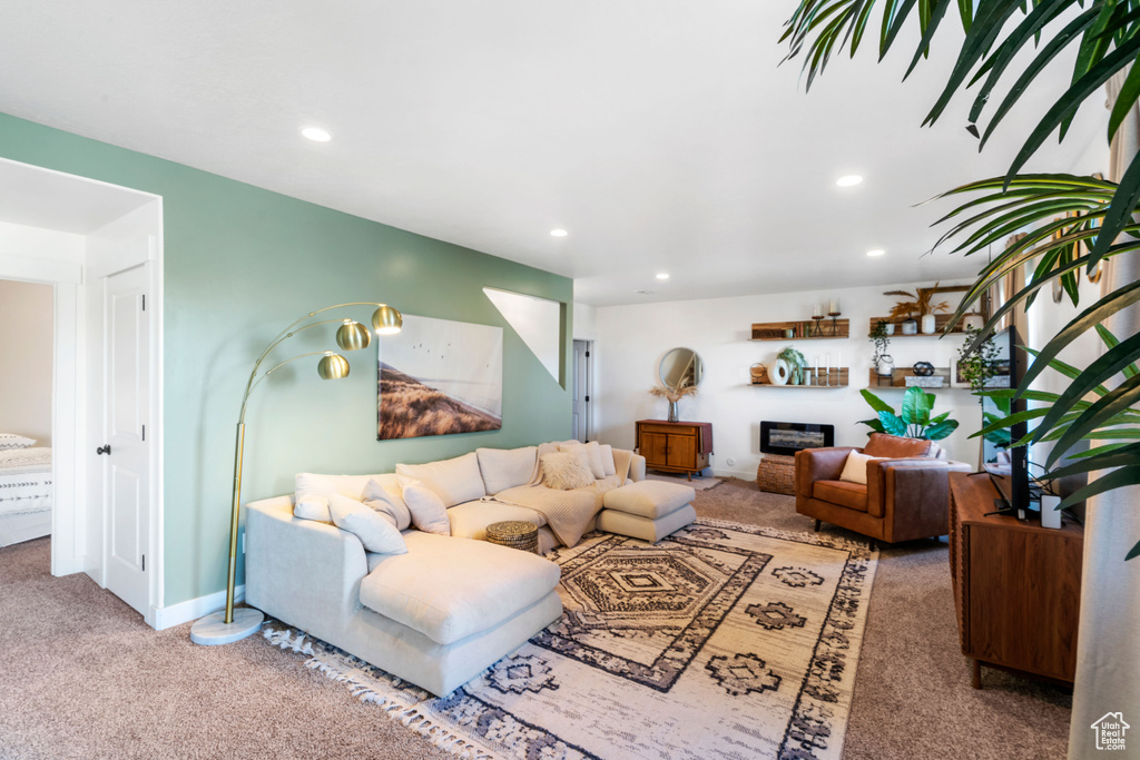 Living room with carpet, recessed lighting, a glass covered fireplace, and baseboards