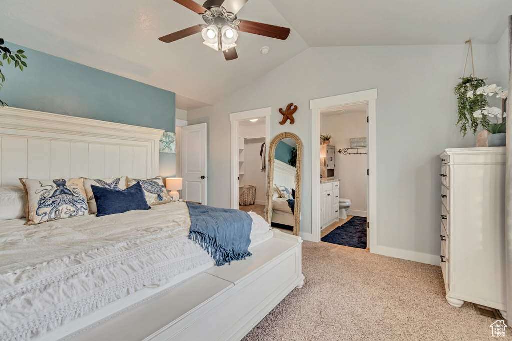 Bedroom featuring lofted ceiling, carpet flooring, ensuite bath, baseboards, and ceiling fan
