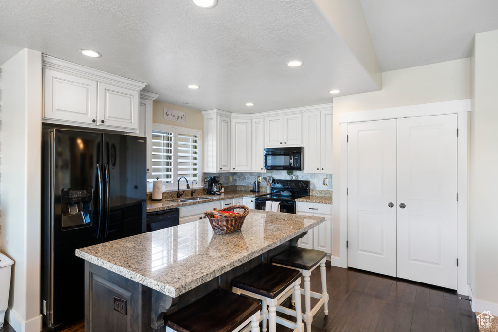 Kitchen with black appliances, a sink, white cabinets, dark wood-style floors, and recessed lighting