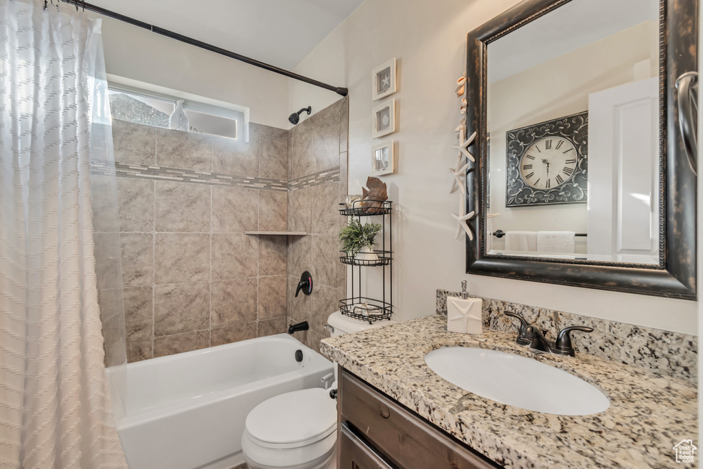 Bathroom with shower / bath combo, vanity, and toilet