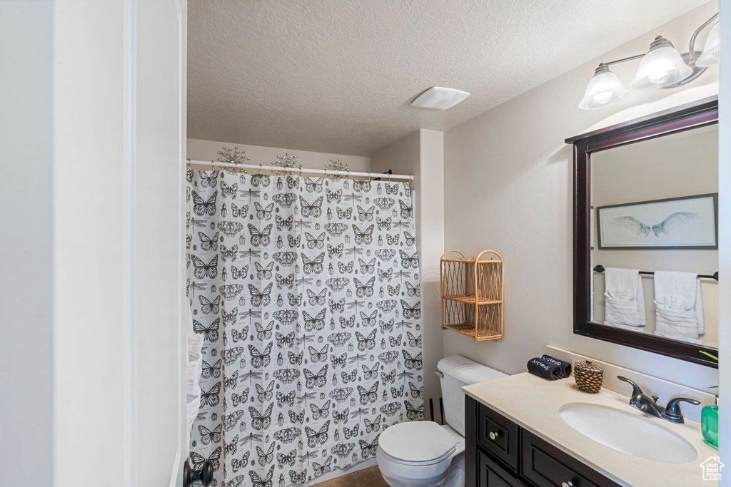 Full bathroom with vanity, a textured ceiling, toilet, and curtained shower