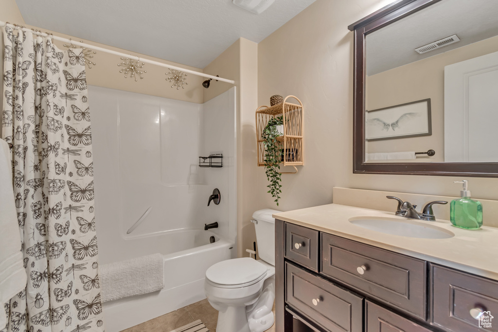 Full bath with vanity, shower / bath combo, toilet, and tile patterned flooring