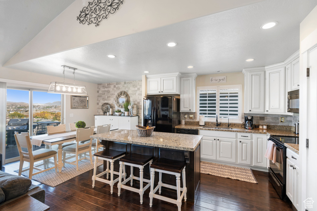 Kitchen featuring black appliances, tasteful backsplash, white cabinets, a kitchen island, and recessed lighting