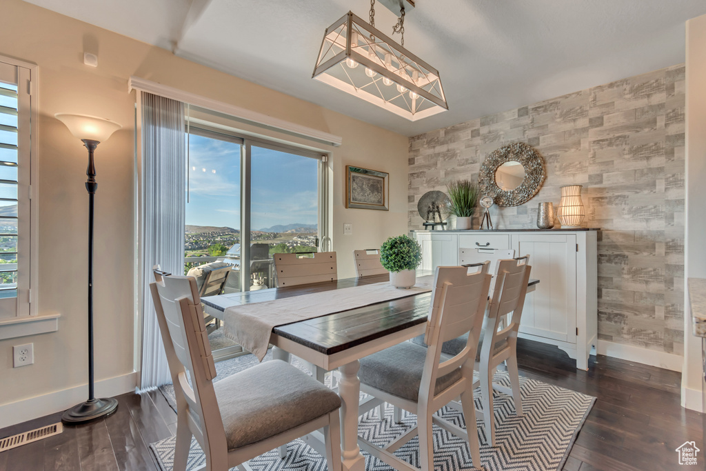 Dining area with an accent wall, plenty of natural light, baseboards, and dark wood-type flooring