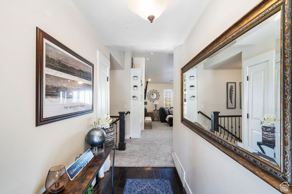 Hallway with an upstairs landing, dark wood-style floors, and baseboards