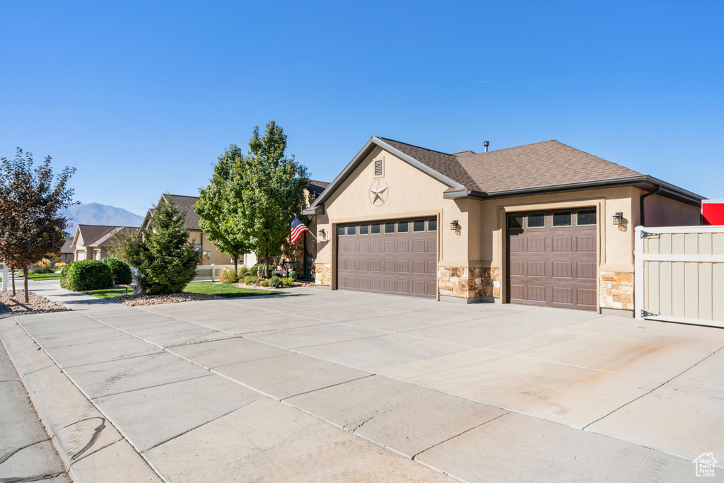 View of front of home featuring stucco siding, concrete driveway, a garage, stone siding, and a shingled roof